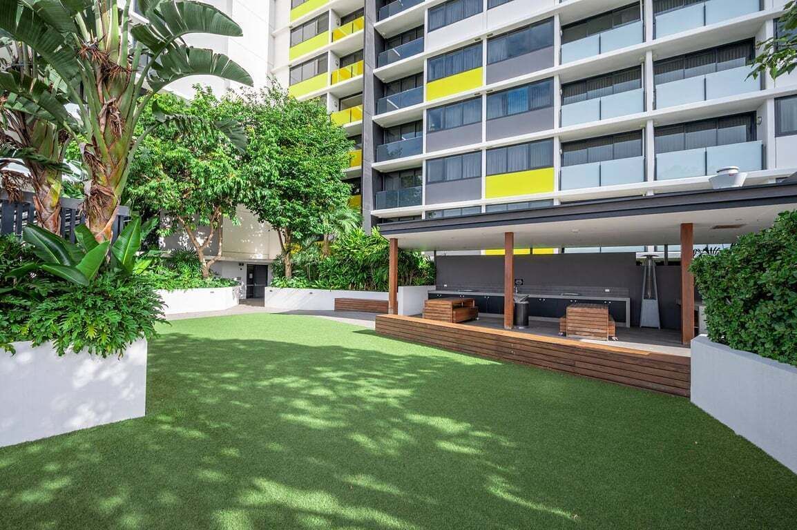 Un edificio moderno con giardino sul tetto, area salotto all'aperto e vegetazione lussureggiante.