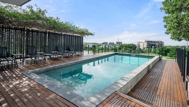 Un área de piscina moderna al aire libre con sillones de descanso y una terraza de madera.