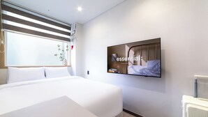 A modern hotel room with a large bed, a mounted TV, and a radiator. - Lazy Tiger Hotel (Seoul)