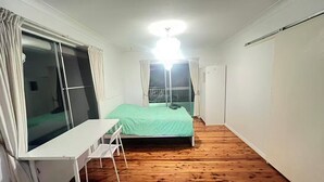 A bedroom with a bed, a desk, and a chair.