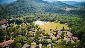 An aerial view of a residential area with houses, a central green space, and a mountain backdrop. - Villa in Pyrenees With Pool & Terrace (Quillan)