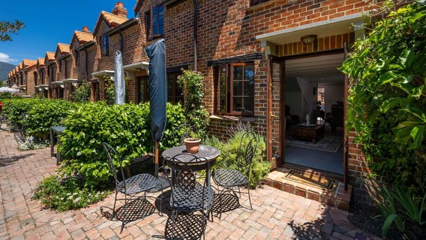 A row of brick houses with a patio area featuring outdoor seating and potted plants. - Relax, Explore, Unwind — Coastal Comfort at The Little Monaco (Nelson)