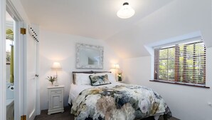 A bedroom with a bed, bedside lamps, a mirror, a window with blinds, and a door leading to another room. - Relax, Explore, Unwind — Coastal Comfort at The Little Monaco (Nelson)