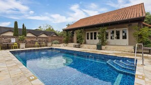 A swimming pool with a tiled deck, a covered patio, and a brick wall. - Relax, Explore, Unwind — Coastal Comfort at The Little Monaco (Nelson)
