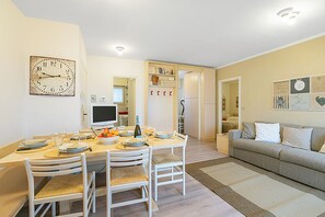 Un coin repas avec une table dressée pour quatre personnes, un téléviseur et une horloge au mur.