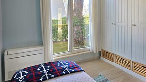 Un dormitorio con cama, ventana, armario y radiador.