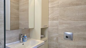 Un baño con lavamanos blanco, un espejo y un perchero para toallas.