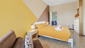 A hotel room with a bed, bedside table, lamp, and a small seating area with a couch and pillows. - La Caravella: Stresa Lake & Islands View Balcony (Stresa)