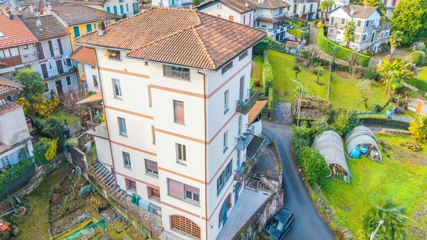 A multi-story building with balconies, a garden, and a street view. - La Caravella: Stresa Lake & Islands View Balcony (Stresa)