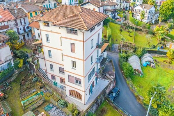 A multi-story building with balconies, a garden, and a street view. - La Caravella: Stresa Lake & Islands View Balcony (Stresa)