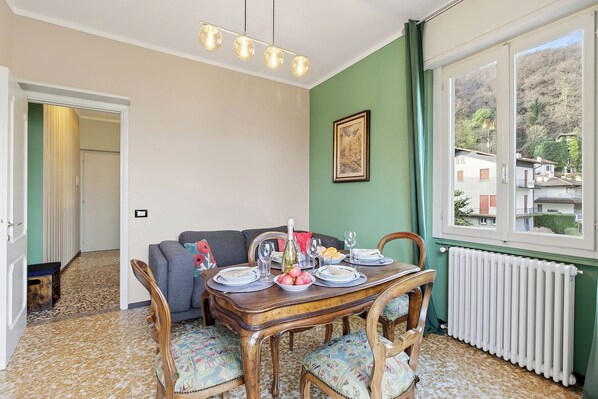 Een eethoek met een houten tafel voor vier personen, een bank en uitzicht op een berg door een raam.