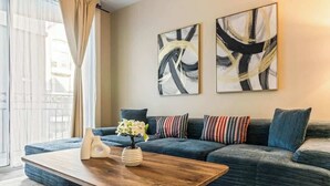 Una sala de estar moderna con un sofá azul oscuro, una mesa de centro de madera y arte abstracto en la pared.