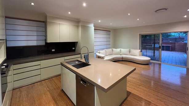 A modern kitchen with a built-in dishwasher, a large island, and a sliding glass door leading to a patio. - 7 mins walking to Bus Station, 5 mins driving to epping train station (Beecroft)