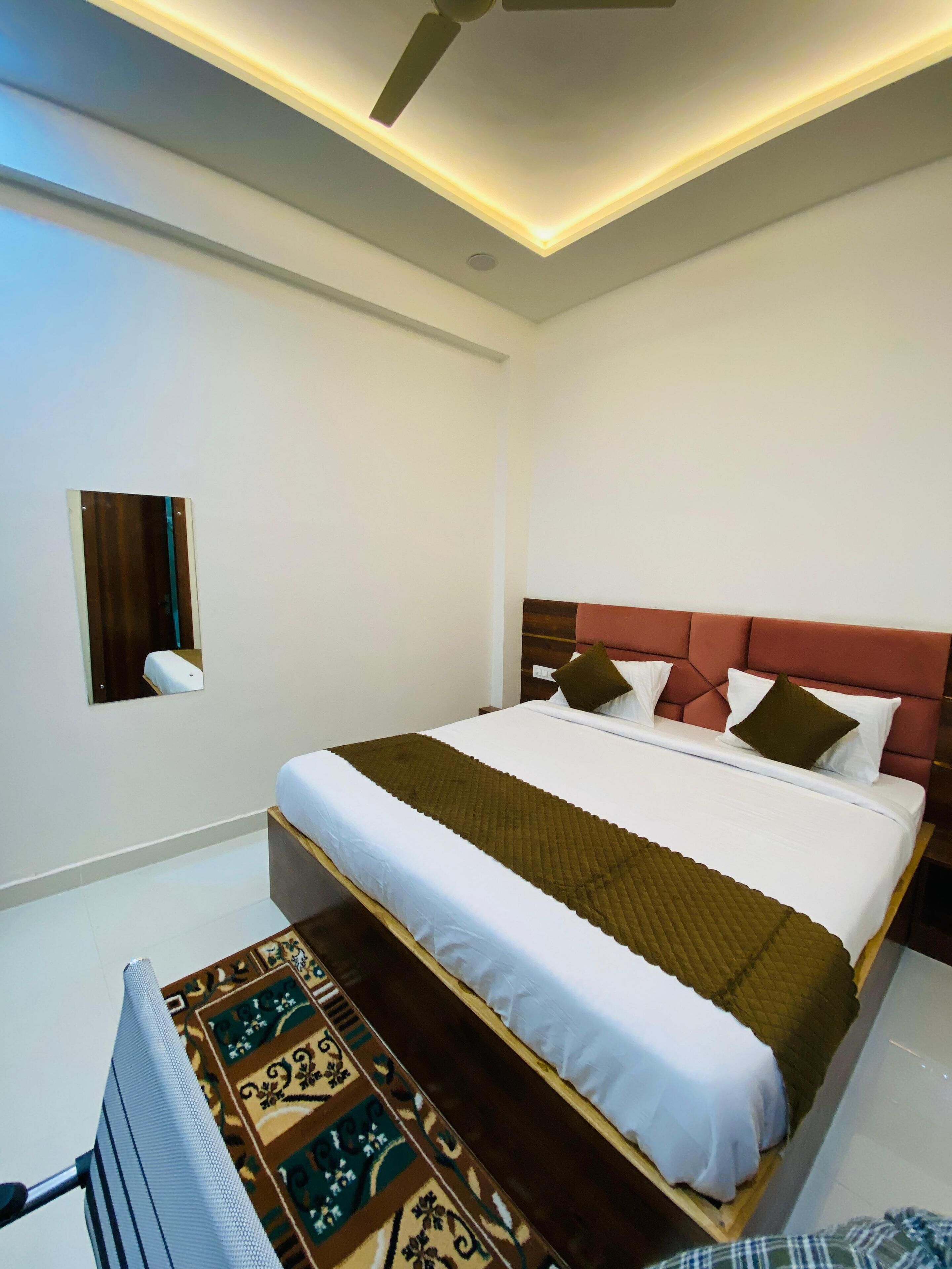 Een moderne hotelkamer met een groot bed, een plafondventilator en een kleine spiegel aan de muur.