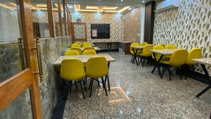A conference room with marble flooring, yellow chairs, and a ceiling with recessed lighting and a fan. - Hotel Taj Silver Palace (Agra)