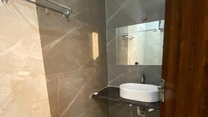 A modern bathroom with a marble wall, a sink, and a mirror. - Hotel Taj Silver Palace (Agra)