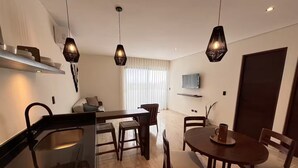 Une cuisine moderne dotée d’une cuisinière intégrée, d’une table à manger en bois et de luminaires suspendus.