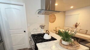 Una cocina moderna con una isla central, una estufa y un comedor con mesa y sillas.