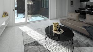 A modern living room with a glass door leading to a balcony, a round coffee table, and a sofa. - THE VELLMORE (Asahikawa)
