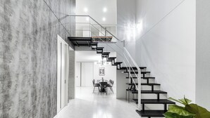 A modern interior with a staircase leading to an upper level, a dining area, and a plant. - THE VELLMORE (Asahikawa)