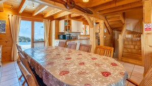 A wooden cabin with a dining area featuring a table set for four, wooden chairs, and a view of the outdoors. - Bleriot T : demi-chalet au pied des pistes (LE GRAND BORNAND)
