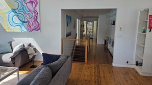 A modern living room with a grey sofa, a coffee table, and a staircase leading to another room. - Island escape with private waterfront beach and jetty on Scotland Island. (Scotland Island)