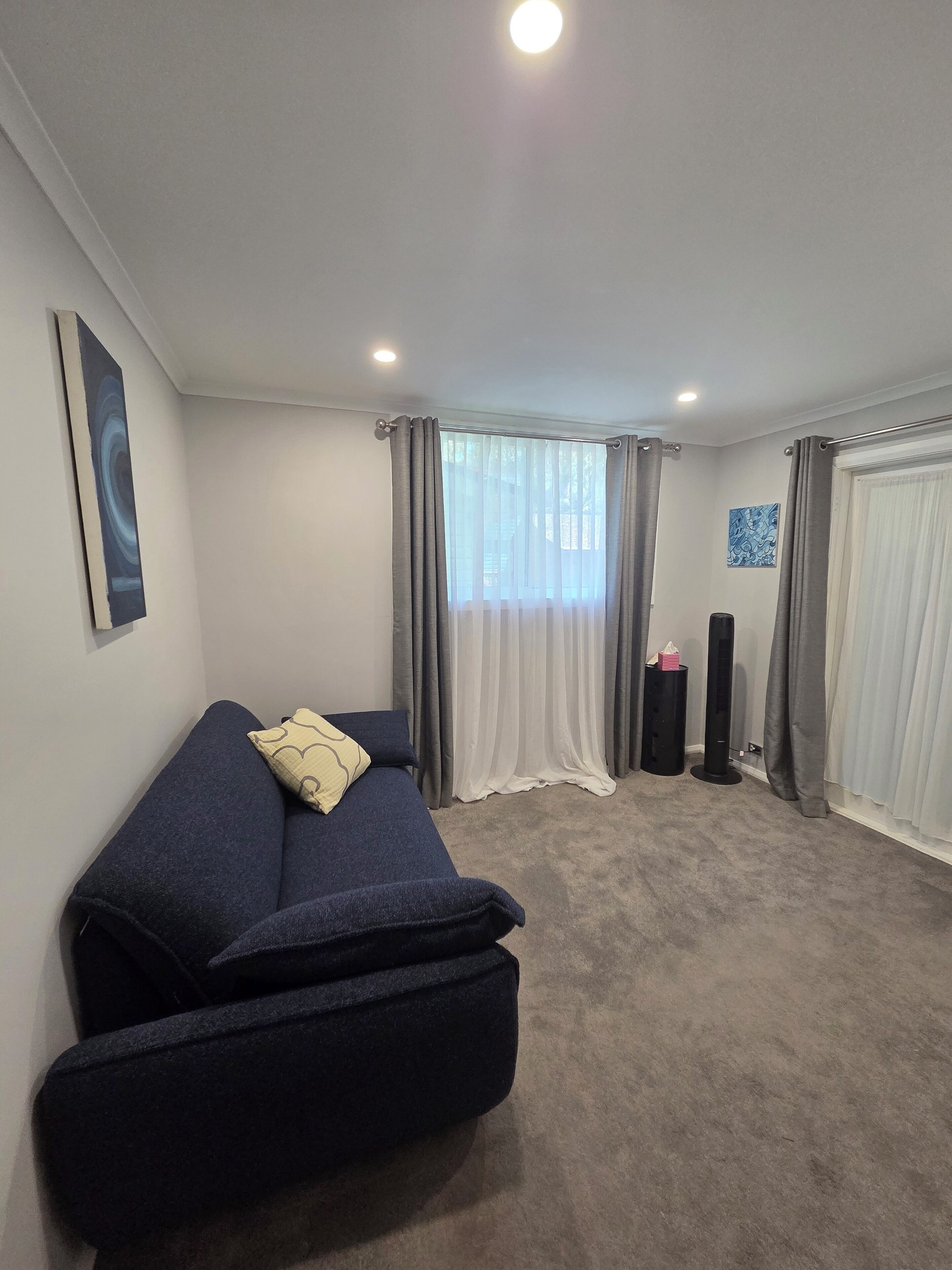 A room with a bed, a punching bag, and a window with curtains.