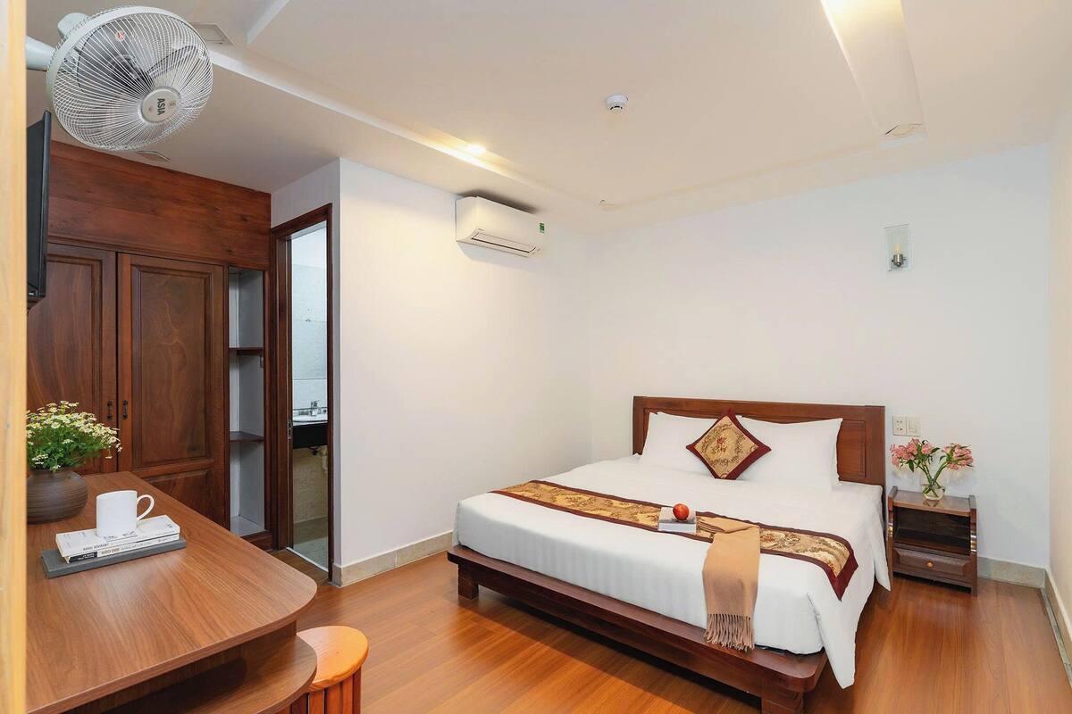 Una habitación de hotel con una cama de madera, una mesita de noche y un escritorio con una silla.