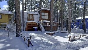 Un rifugio imbiancato dalla neve con facciata in legno, un garage e un cortile recintato.