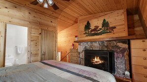 Una camera da letto in legno accogliente, con camino in pietra, pareti in legno e un letto con coperta a righe.