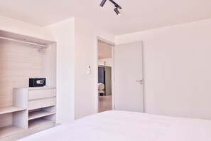 A minimalist bedroom with a bed, a walk-in closet, and a door leading to another room. - Apartment 4B Doña Raquel in Panama City (Panama City)