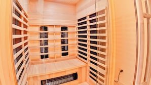 Uma sauna com paredes e bancos de madeira, sistema de ventilação e porta de metal.