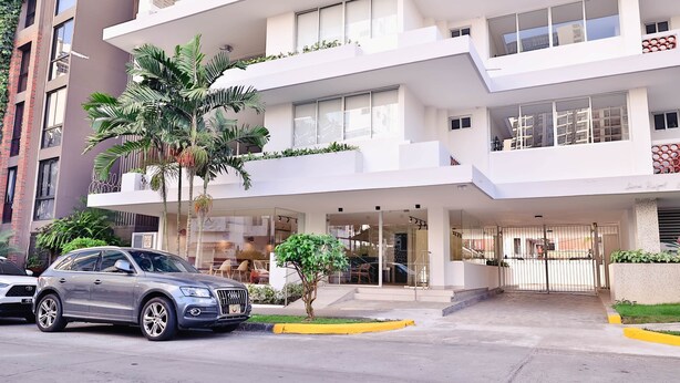 Un hôtel moderne à la structure à deux étages, doté de grandes fenêtres et d’une entrée sécurisée par un portail.