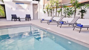 Un espace piscine avec des chaises longues et un panneau d’affichage.