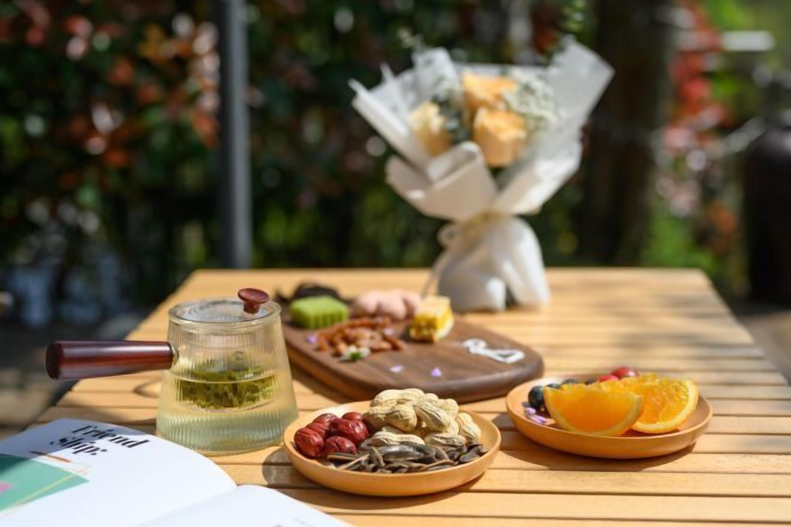 A table with a glass of tea, a plate of nuts, and a plate of fruit.