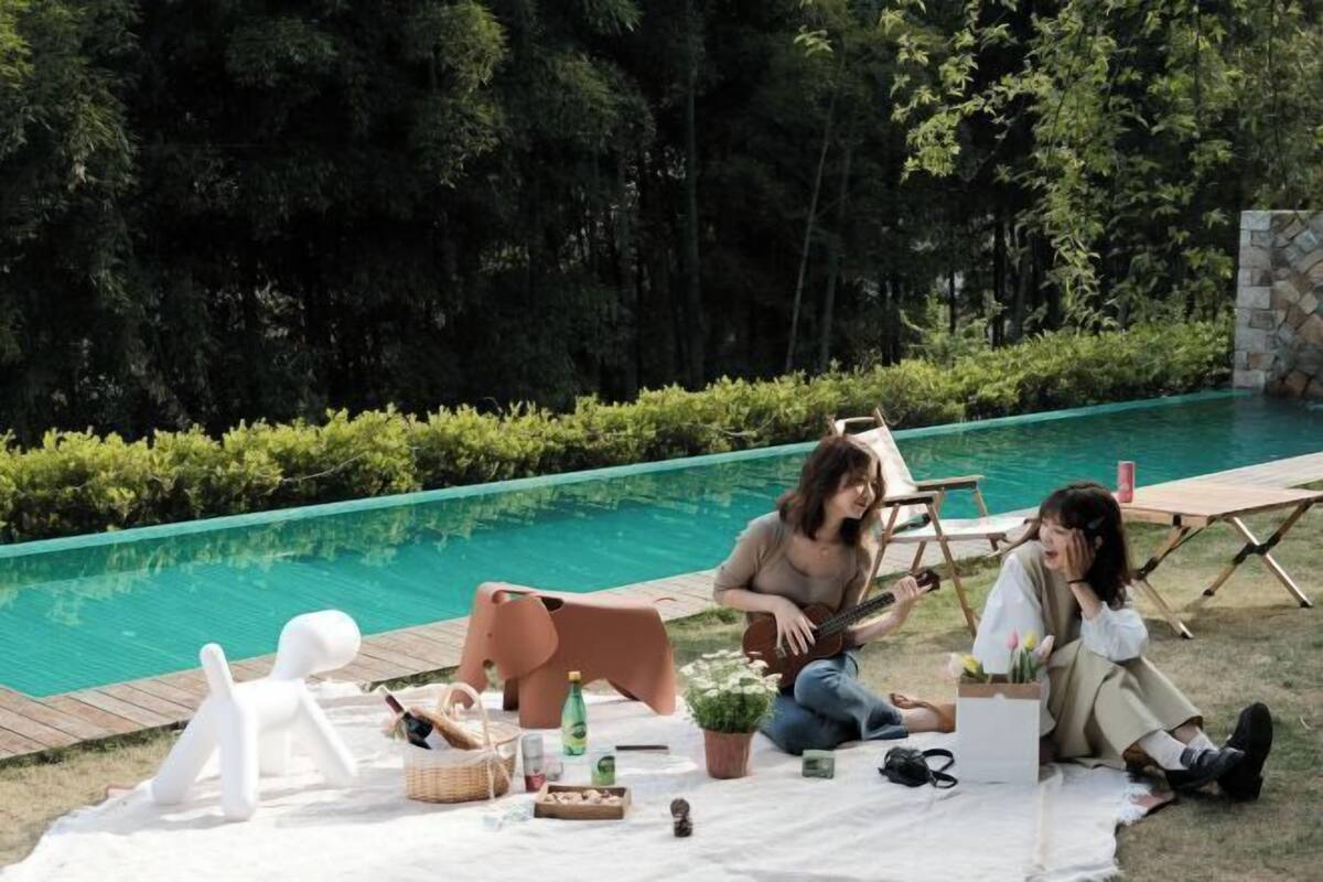 A poolside area with a wooden deck, lounge chairs, and a picnic setup.