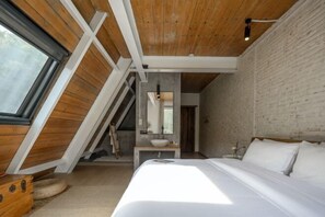 A bedroom with a sloped ceiling, a bed, a bedside table, a mirror, and a window. - Caotu·Building Meisu (Moganshan) (Deqing)