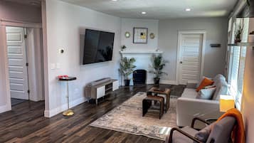 A modern living room with a flat-screen TV, a fireplace, and a cozy seating area.