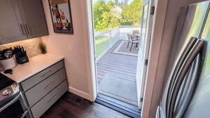 A kitchen with a sliding glass door leading to a balcony with outdoor seating. - Vibrant 4-Bed Perry District Unit: Full Kitchen, Outdoor Living – Groups' Dream! (Spokane)