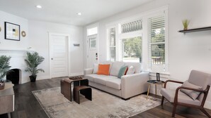 A spacious living room with a white sofa, a coffee table, and a fireplace. - Vibrant 4-Bed Perry District Unit: Full Kitchen, Outdoor Living – Groups' Dream! (Spokane)