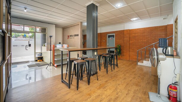 Un espace bar moderne avec un plancher en bois, des tabourets de bar en métal et un long comptoir.