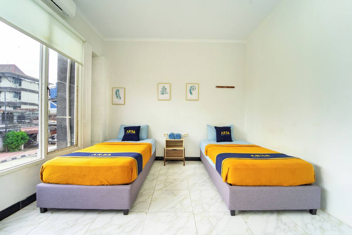 Een hotelkamer met twee bedden, een tafeltje en een raam.