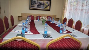 A conference room with a long table, red chairs, water bottles, and a framed picture on the wall. - Prestige Guest House Karatina (Karatina)