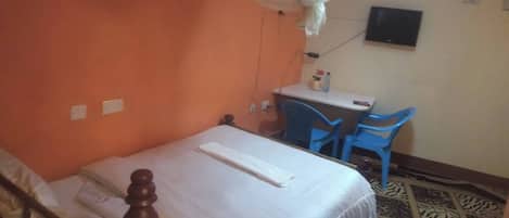 A bedroom with a bed, a desk, and two chairs.