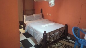 A single bed with a white bedspread and pillows, a wooden headboard, a blue plastic chair, and a checkered floor pattern. - Prestige Guest House Karatina (Karatina)