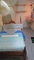 Una cama con dosel, una mesita de noche y un lavamanos pequeño.