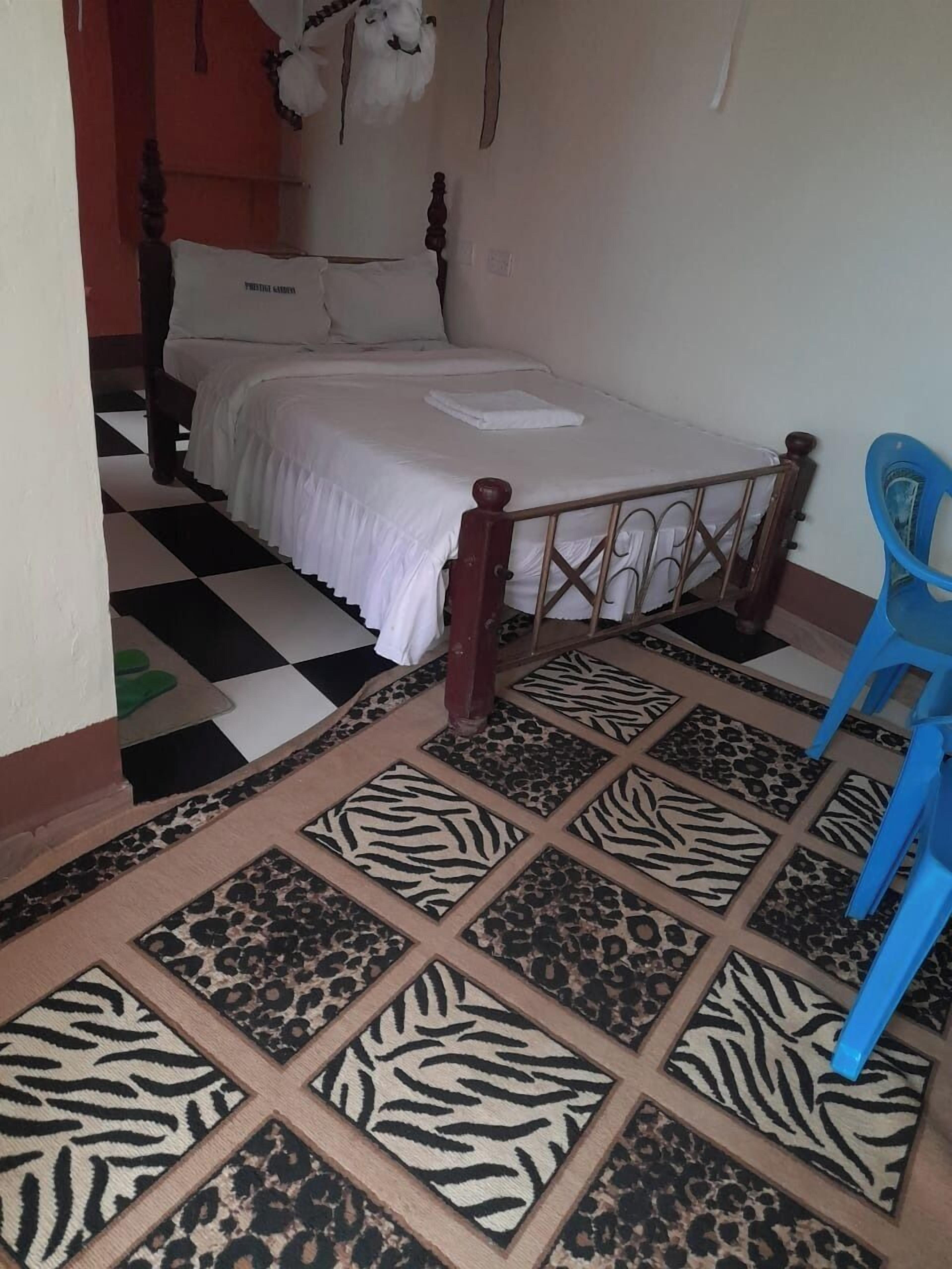 A bedroom with a bed, a blue chair, and a checkered floor.