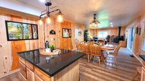 Un intérieur en bois comprenant un îlot de cuisine, un coin repas et une cheminée.