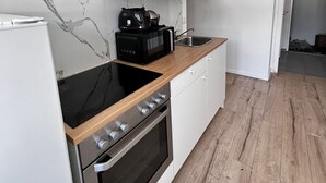 Een moderne keuken met witte kastjes, een zwart inductiekookveld en een roestvrijstalen oven.