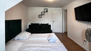 Een moderne hotelkamer met een groot bed, een flatscreen televisie aan de muur en een trap naar een andere kamer.